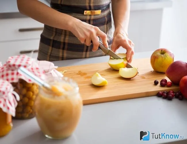 Женщина режет яблоки для варенья.